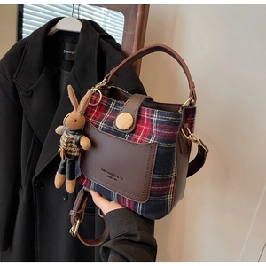 Detail of vintage plaid bucket bag with brown leather trim and cute rabbit charm accessory