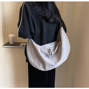 Grand sac à bandoulière en toile grise pour femme porté par un mannequin pour le style