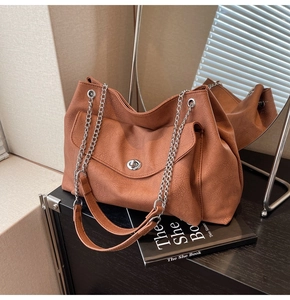 Detail of caramel brown tote bag with silver chain strap and lychee texture finish