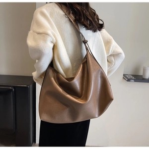 Brown leather large capacity hobo bag with texture shown on model in warm natural light