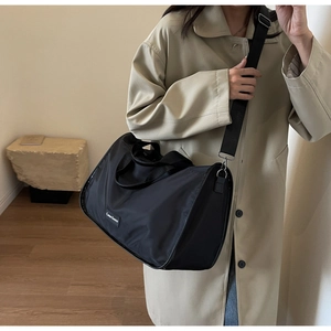 Close-up of black nylon large capacity bag worn crossbody with beige trench coat