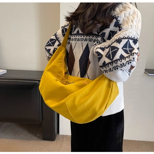 Détail d'un sac hobo croissant jaune en nylon avec large bandoulière sur mannequin