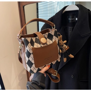 Detail of checkered crossbody bag with brown leather trim and cute bunny charm accessory