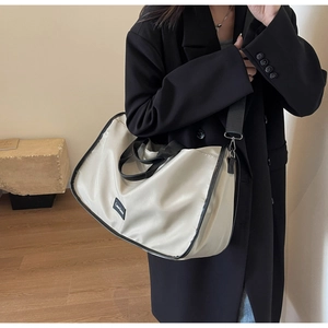 Close-up of cream nylon tote bag with black straps and adjustable wide shoulder strap