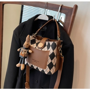 Detailed view of bucket bag featuring black and white diamond canvas and a cute bunny charm
