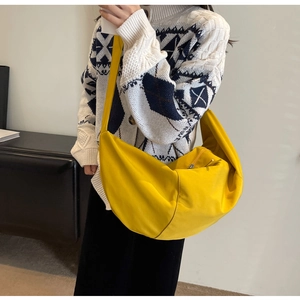 Modèle portant un sac bandoulière en toile jaune vif en forme de croissant moderne