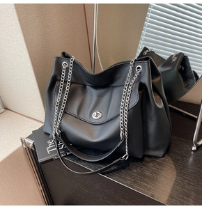 Macro shot of large black faux leather tote with silver twist-lock pocket and chain strap