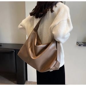 Close-up of soft brown leather tote bag with wide shoulder strap and refined texture