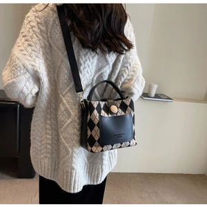 Detail of argyle bucket bag with leather pocket and wooden button in lifestyle setting