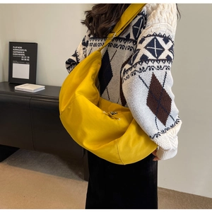 Sac bandoulière jaune en toile en forme de croissant porté sur un pull d'hiver à motifs