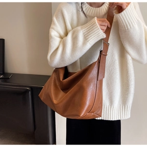 Detail of a large brown faux leather tote with adjustable wide strap and metallic buckles