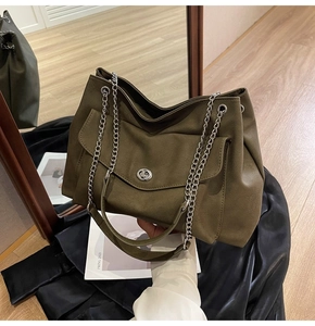 Detail view of large tote bag with silver chain strap and twist-lock on matte green leather