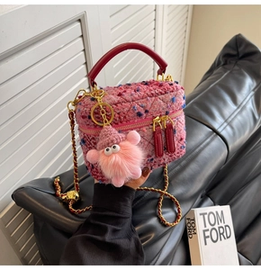 Detailed close-up of pink tweed bucket bag with red handle and gold chain strap