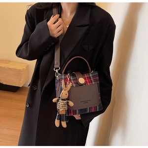 Detail of British plaid handbag featuring a wooden buckle and a cute rabbit charm