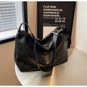 Detail of matte black leather tote bag showing soft hobo texture and silver metal buckle