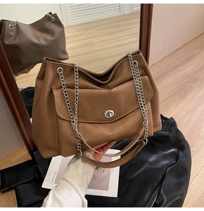 Close-up of brown faux leather tote with silver twist lock and chain strap details