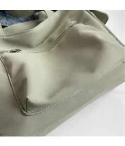 Detail showing soft olive green canvas texture and metal zipper pocket of this tote bag