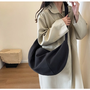 Vue latérale d'un grand sac croissant en toile noire montrant le drapé sur le mannequin