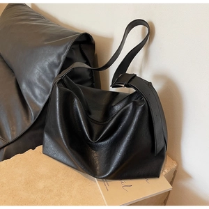 Close-up of black matte PU leather tote bag showing pleated texture and silver buckle