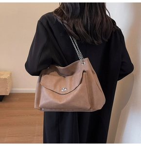 Detail of dark brown leather tote bag with silver chain strap and metal swivel lock buckle