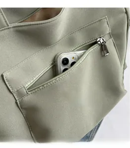 Close-up of the light green canvas tote showing the front zipper pocket for smartphone storage