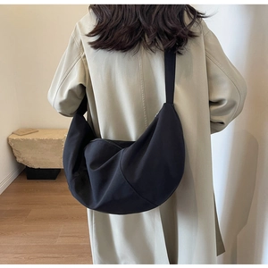 Sac croissant noir minimaliste porté par un mannequin dans un intérieur épuré