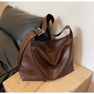 Detail of dark brown leather texture and adjustable strap on large hobo shoulder bag