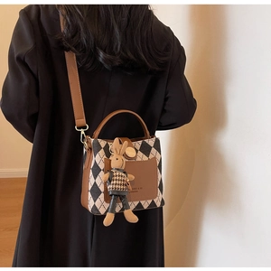 Detail of quilted bucket bag with leather trim and cute bunny charm accessory