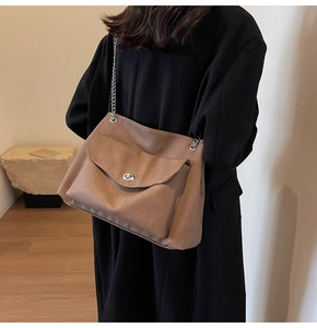 Detail of vintage brown leather tote bag with silver chain strap and metal turn-lock closure