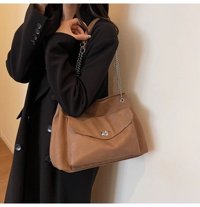Close-up of caramel brown tote bag featuring silver chain strap and metal twist lock