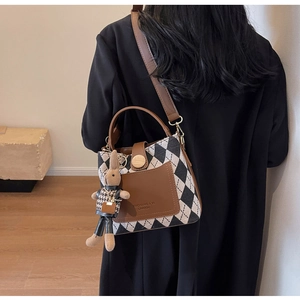 Detail showing the knitted plaid handbag with leather accents and bunny charm on a model