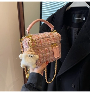 Close-up of pink tweed mini bag with gold chain strap and plush pendant accessory