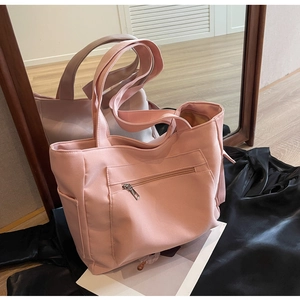 Pink canvas tote bag featuring functional front zipper and side pockets for storage