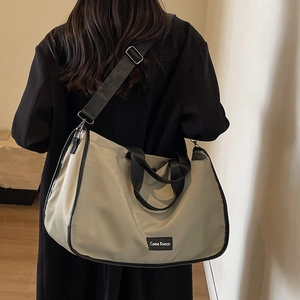 Large capacity beige nylon tote bag with black adjustable strap shown on a model