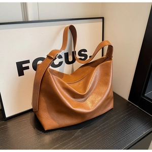 Detail of caramel leather hobo bag showing adjustable strap and silver metal hardware buckle