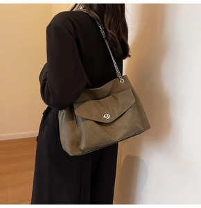 Detail of olive green tote bag with silver chain strap and front flap pocket closure