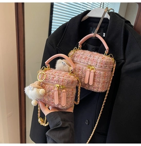 Detail of pink tweed mini bag with leather handles and cute plush elf charms