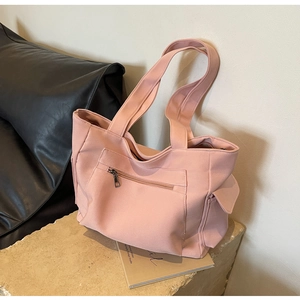 Detail of pink canvas tote bag showing side pocket with flap and zipper compartment