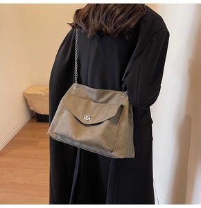 Detail of khaki green chain shoulder bag with metal lock shown on a model's back