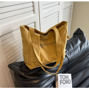 Macro detail of a bright yellow canvas tote bag with front zipper and wide shoulder strap