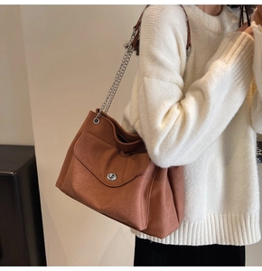 Detail of vintage brown leather shoulder bag featuring metal chain strap and twist lock
