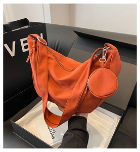 Gros plan d'un sac demi-lune en nylon orange avec mini porte-monnaie et boucles argentées