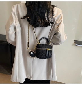 Detail of black faux fur bucket bag with gold chain strap and soot sprite plush charm