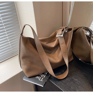 Macro detail of brown leather tote bag showing lychee grain texture and vintage buckle