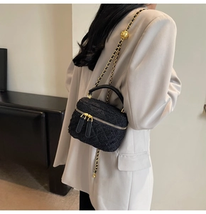 Detail of tweed crossbody bag with adjustable gold ball chain shown on beige blazer