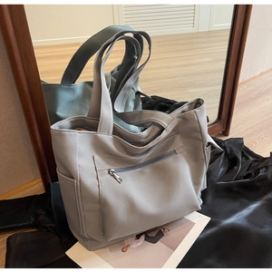 Detailed macro view of gray canvas tote bag featuring side pockets and a zipper pocket