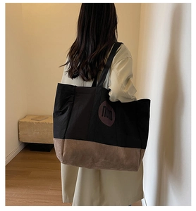 Détail du sac cabas en toile avec surpiqûres contrastées et logo nuna sur l'épaule