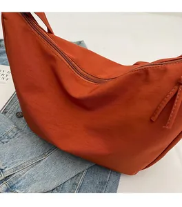 Détail du sac croissant orange doux avec texture en nylon et cordon décoratif