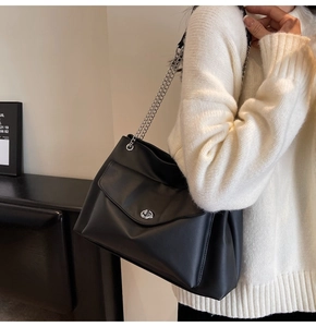 Detail of black matte tote bag with silver chain strap and metal turn-lock closure
