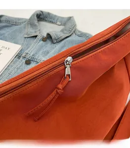 Gros plan du curseur en métal argenté avec tirette orange nouée sur sac en toile